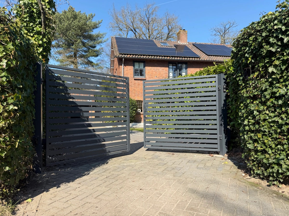 Modern donker hekwerk langs de oprit van een woning