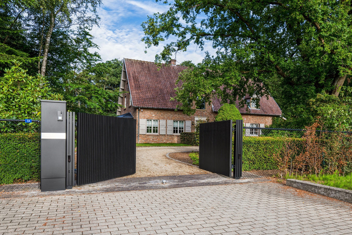 Openstaande antracieten inrijpoort met zuil voor een vrijstaande woning